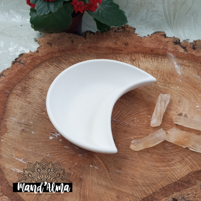 prato branco em forma de crescente sobre madeira com cristais e flores vermelhas ao fundo