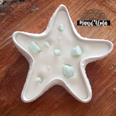 Vela branca em forma de estrela com pedras verdes sobre madeira