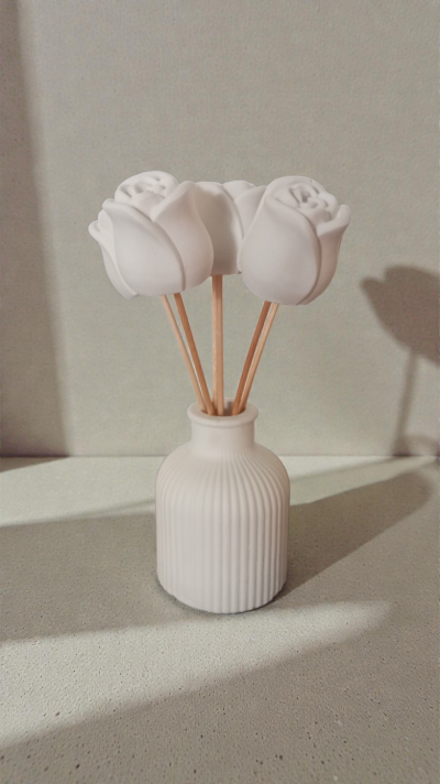 Frasco branco com flores artificiais brancas em forma de rosa