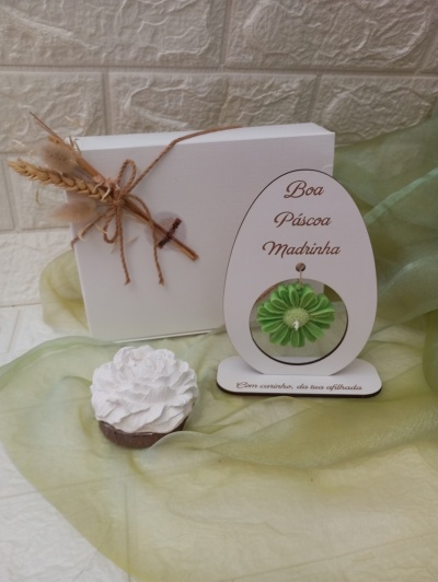 Conjunto de oferta de Páscoa com caixa branca decorada, vela branca em forma de flor e placa em forma de ovo com flor verde e texto