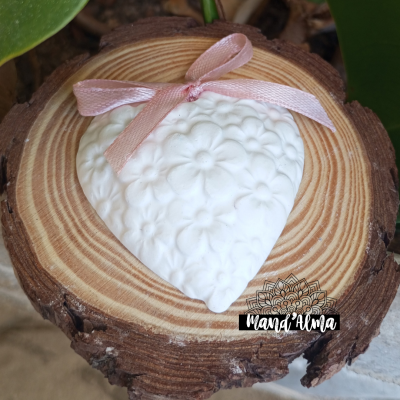 Coração decorativo branco com flores em relevo e fita rosa numa madeira redonda