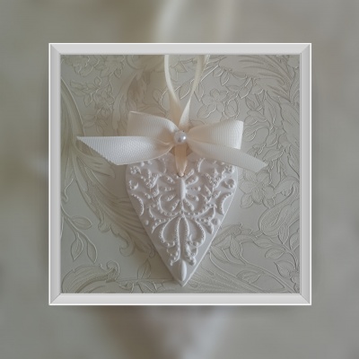 Ornamento branco em forma de coração com laço e padrão floral em relevo