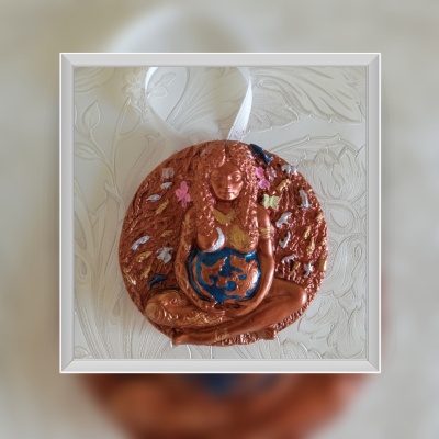 Escultura decorativa de resina de uma figura feminina com detalhes coloridos em fundo texturizado.