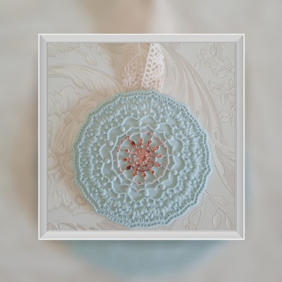 Adorno redondo em tecido azul com detalhes cor de salmão e fita transparente com bolinhas