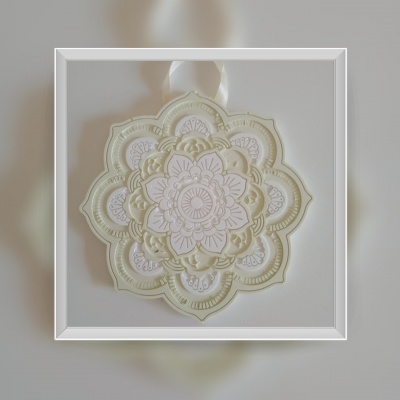 Ornamento decorativo em formato de mandala em branco e creme com textura em relevo, pendurado