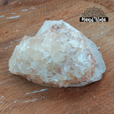 Pedra mineral com cristais brancos e amarelos sobre base cinzenta em superfície de madeira