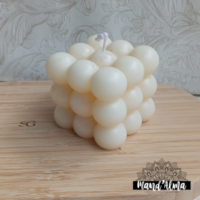 Vela branca em forma de cubo feita de esferas sobre base de madeira clara