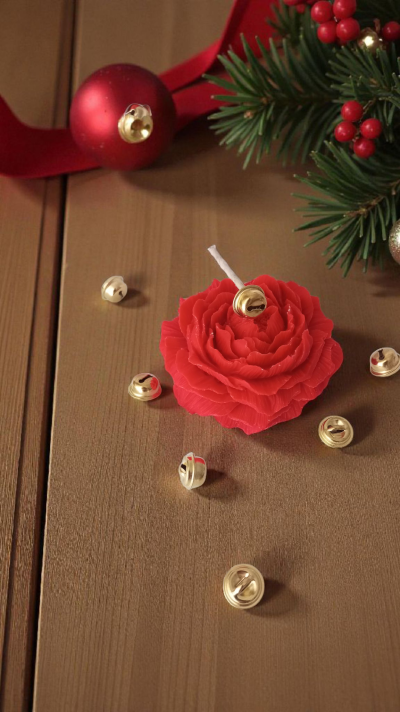 Vela vermelha em forma de flor com sinos dourados e decoração de Natal em fundo de madeira