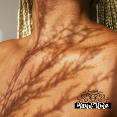 Sombras de planta sobre pele bronzeada com tranças loiras e logotipo Mand'Alma.