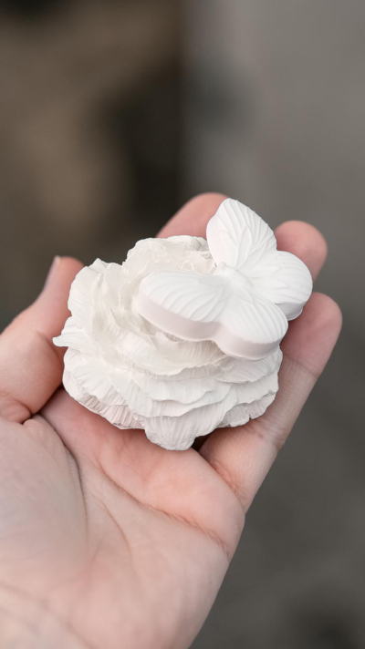Escultura branca de flor e borboleta na mão