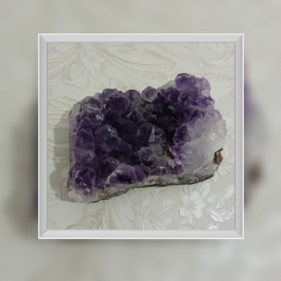 Cristal mineral roxo e branco sobre tecido floral claro