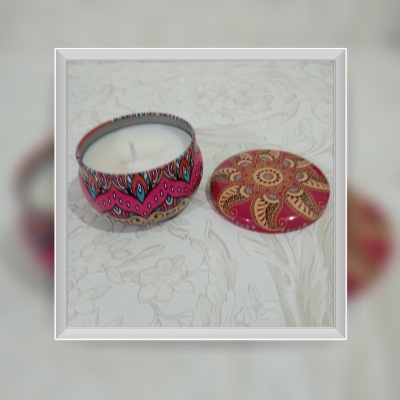 Vela branca em lata decorativa colorida com tampa floral dourada e rosa ao lado