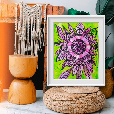 Pintura mandala rosa e roxa em moldura branca junto a almofada redonda de fibras naturais e banco de madeira
