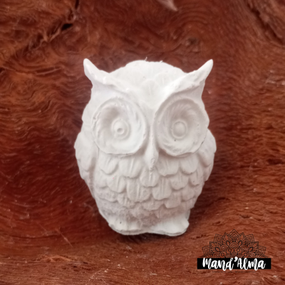 Escultura branca de coruja sobre madeira marrom