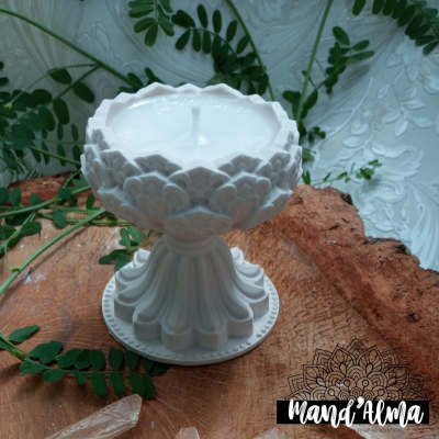 Vela branca em suporte cerâmico decorativo em forma de flor sobre madeira rústica