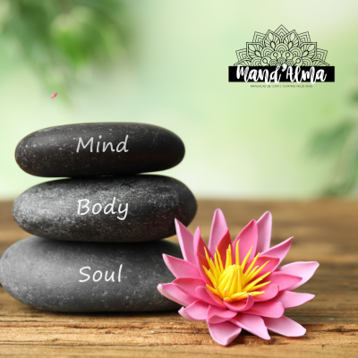 Pedras empilhadas com palavras Mind, Body, Soul e uma flor de lótus rosa sobre superfície de madeira