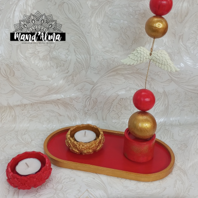 Conjunto decorativo com velas e ornamento esferas em vermelho, dourado e branco sobre base oval vermelha e bege com padrão floral.