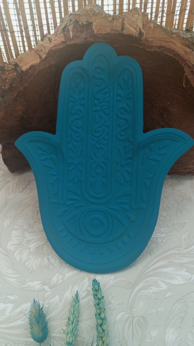 Estatueta azul em forma de mão de fatima com olho central e padrões gravados