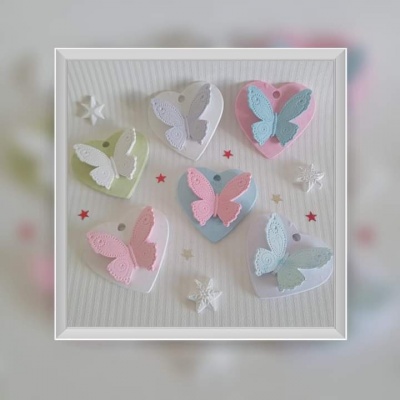 Seis corações coloridos com borboletas em relevo sobre fundo claro com estrelas