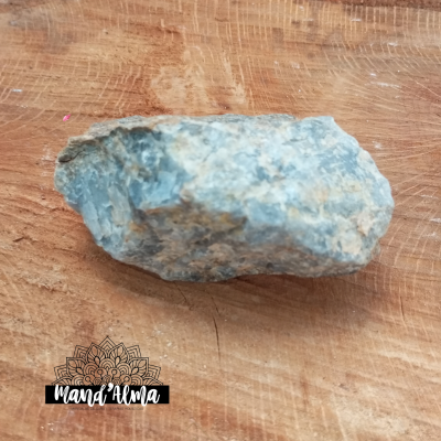 pedra azul esverdeada bruta sobre mesa de madeira com logótipo Mand'Alma