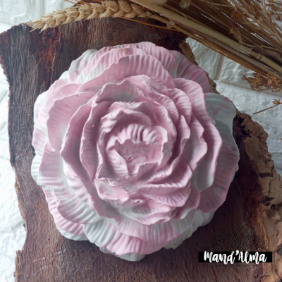 Flor decorativa de cerâmica rosa e branca sobre madeira rústica com espigas de trigo secas