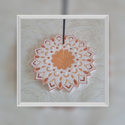 Incensário em formato de flor branco e dourado com incenso aceso