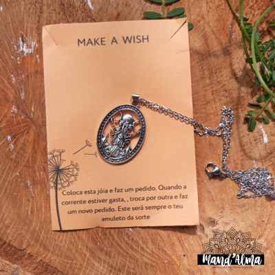 Colar com pendente oval metálico em cartão com instruções, sobre madeira e folhas verdes