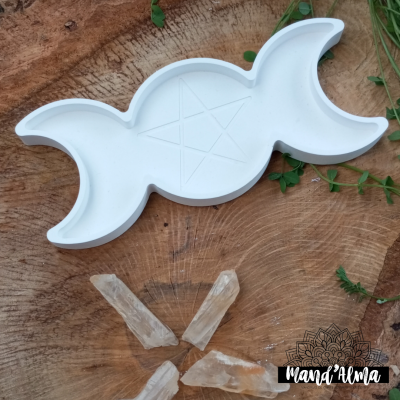 Prato branco em forma de lua tripla com pentagrama em relevo sobre madeira rústica, cristais e folhas verdes