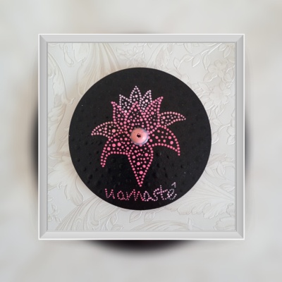 Prancha redonda preta com desenho de flor cor-de-rosa e texto namastê