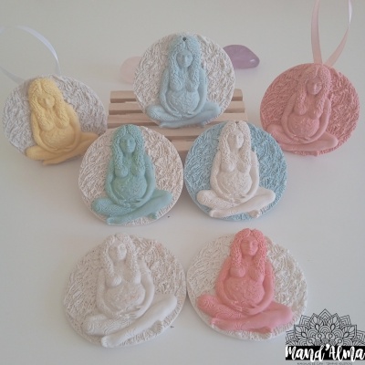 Ornamentos redondos em gesso com figuras femininas coloridas em posição de meditação.