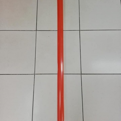 Barra longa de plástico vermelho sobre chão de azulejos brancos