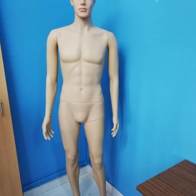 Manequim masculino cor bege em pé contra parede azul em canto de sala