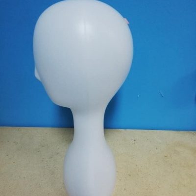 Expositor busto branco em plástico sobre superfície bege e fundo azul