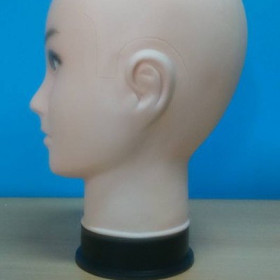 Cabeça de manequim de plástico bege claro com base preta sobre mesa de madeira frente a fundo azul