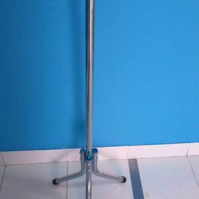 Suporte metálico com três pernas e ligação azul, sobre chão branco e parede azul