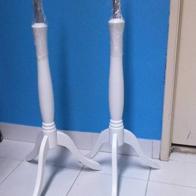 Dois manequins de madeira branca com hastes cobertas por plástico em chão de azulejos frente a parede azul