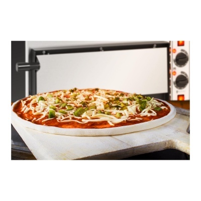 Pizza crua com queijo e molho sobre pá de madeira em frente a forno