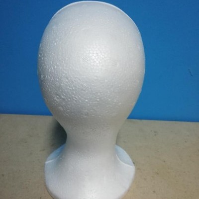 Cabeça de manequim de espuma branca sobre superfície bege com fundo azul