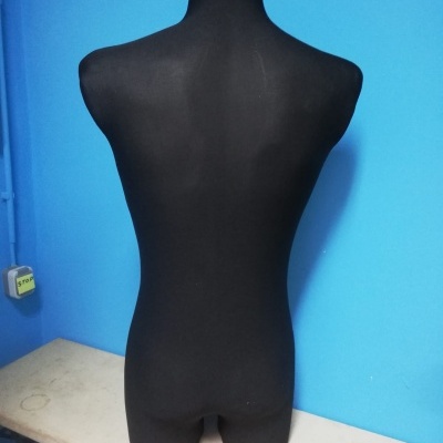 Manequim torso masculino preto sobre mesa branca e parede azul