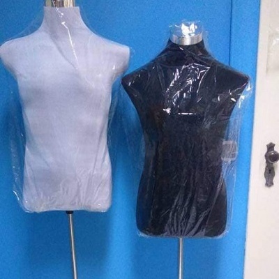 Dois manequins de tecido branco e preto protegidos com plástico em fundo azul