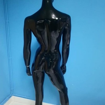 Mannequim preto brilhante contra parede azul e chão de azulejos brancos