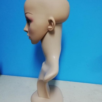 Cabeça de manequim em plástico cor de pele com maquilhagem, numa base contra fundo azul