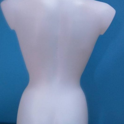 Manequim branco translúcido de costas sobre superfície de madeira e fundo azul