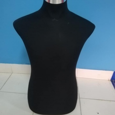 Manequim de torso preto com topo prateado em chão de azulejos brancos e parede azul