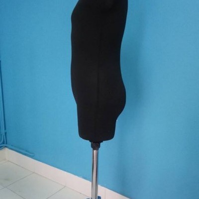 Manequim de costura masculino preto numa sala com parede azul e chão branco