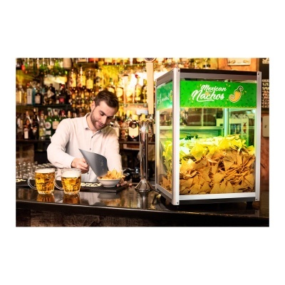 Expositor de nachos mexicanos iluminado com três copos de cerveja e homem a servir-se no balcão