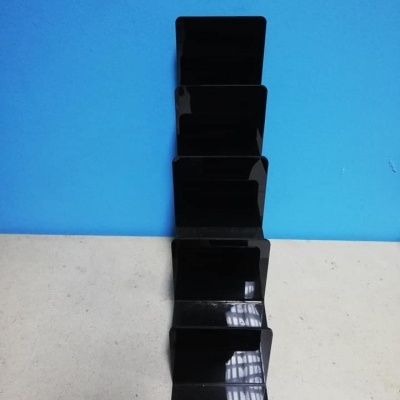 Suporte preto de plástico com divisórias verticais em fundo azul e superfície clara