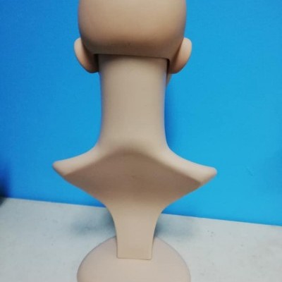 Busto plástico bege visto de costas com base oval em fundo azul.