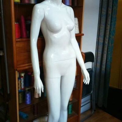 Mannequim feminino branco brilhante em pé junto a armário com linhas coloridas
