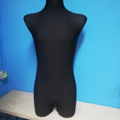 Mannequin torso in black on table against blue wall